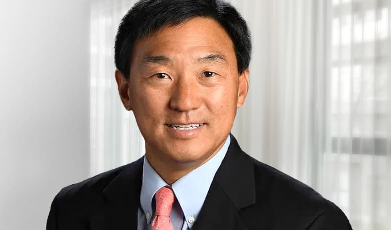 Dr. Frederick K. Park smiling, wearing black suit with coral tie