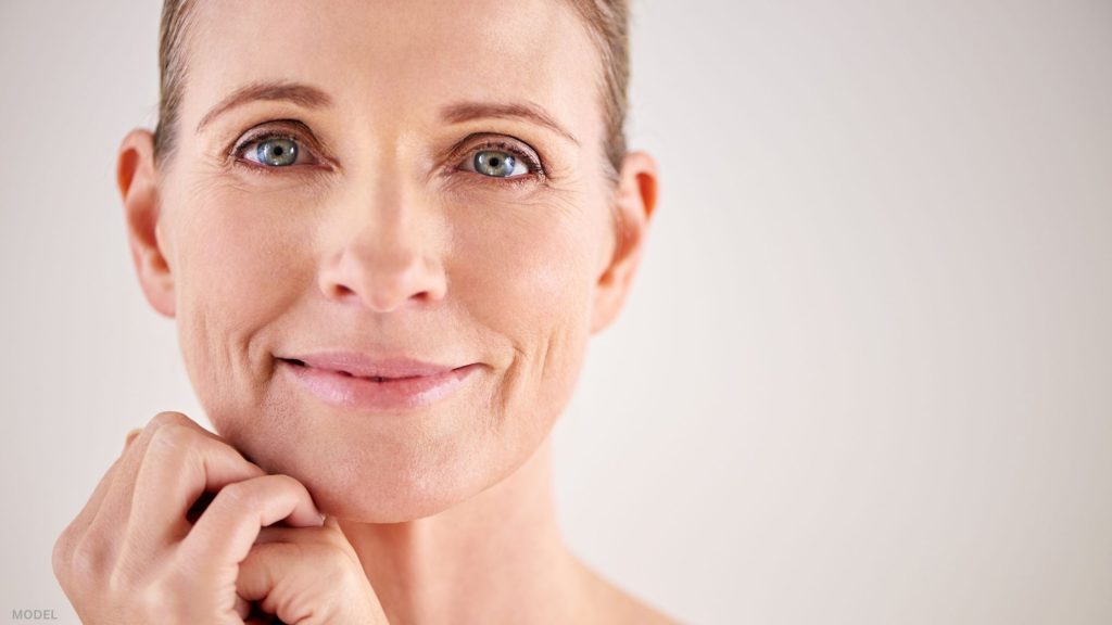 Mature woman looking forward with hands on face (model)