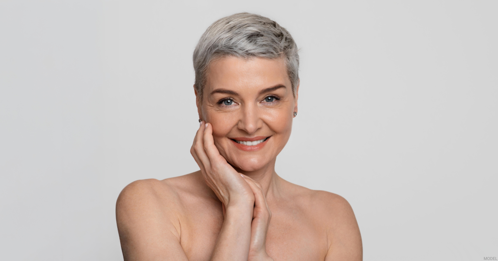 Woman smiling with one hand resting on her cheek. (model)